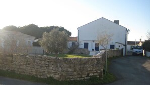 A white building with a stone wall and a tree in front.