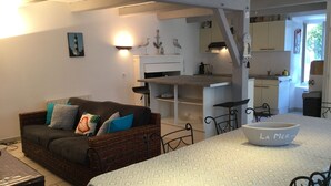 A cozy living room with a sofa, a dining table, and a kitchen area.