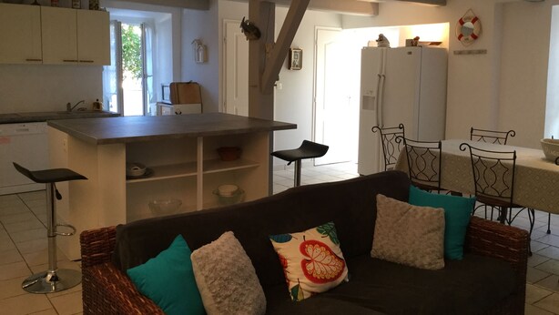 A modern kitchen with white cabinets, a central island, and a dining area with a table and chairs.