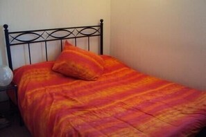 Ein Bett mit schwarzem Metallgestell und einer farbenfrohen Decke.