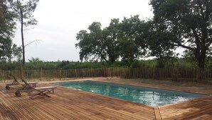 Ett trädäck med en swimmingpool, omgivet av ett trästaket och träd.