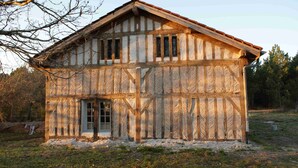 Une maison traditionnelle à colombages, avec un toit à pignon, une porte centrale et une petite fenêtre à l’étage supérieur.