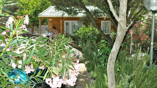 A wooden house with a tiled roof, surrounded by lush greenery and flowering plants. - 2/4-person CLIMATIZED WOODEN CHALET CLOSE TO ALGAJOLA village views (Algajola)