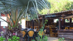 An outdoor dining area with tables and chairs, surrounded by plants and a palm tree. - 2/4-person CLIMATIZED WOODEN CHALET CLOSE TO ALGAJOLA village views (Algajola)