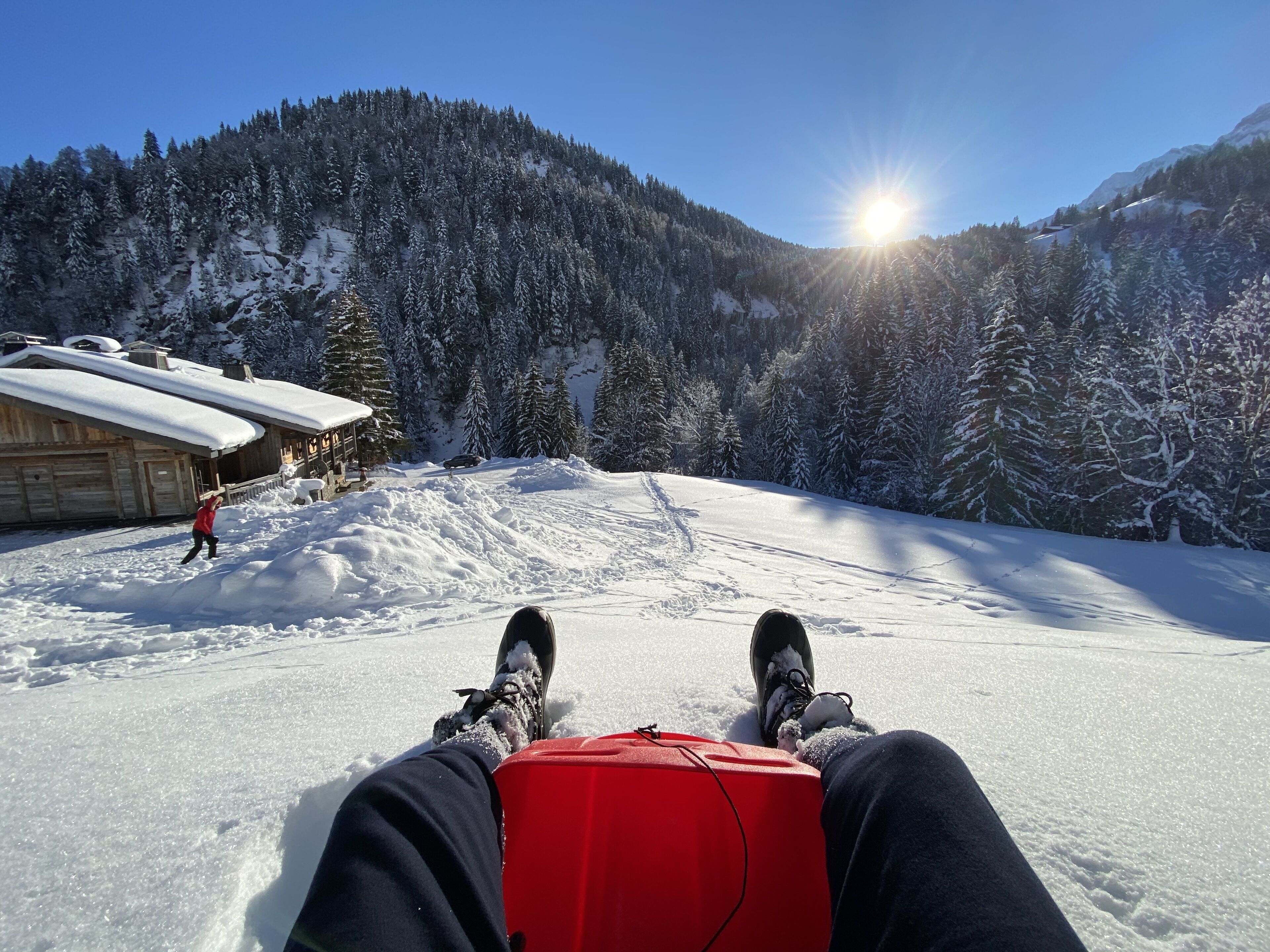 A snowy mountain landscape with a wooden cabin and a person skiing.