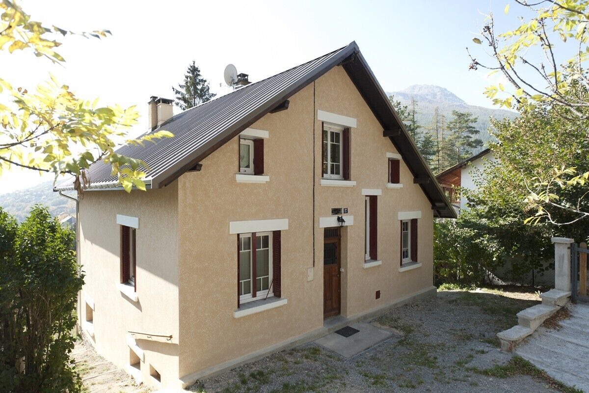 A two-story house with a sloped roof, multiple windows, and a small front porch.