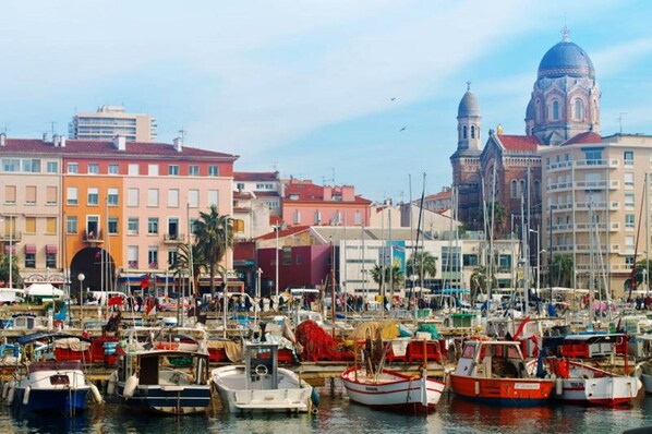Uma marina com barcos atracados, cercada por edifícios coloridos e uma igreja imponente com cúpulas.