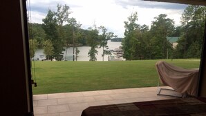 A room with a view of a lake, a covered patio, and a bed with a patterned bedspread. - Lake Front, Walk out ground level, Sunset VIEW, Dedicated Slip, Awesome Pool (Dadeville)