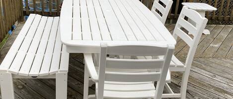 A white wooden deck with a table and four chairs.