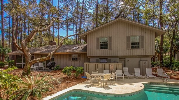 A two-story house with a swimming pool, outdoor seating, and a wooded backdrop. - 4th Row Ocean Home w/ Private Pool (Hilton Head Island)