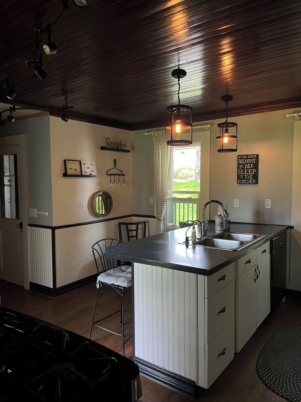 A kitchen with a central island, pendant lighting, and a view of the outdoors.