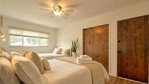 A bedroom with two beds, a ceiling fan, a window with blinds, a wooden door, and a potted plant. - OCEANFRONT! BEST LOCATION! EXTRAORDINARY VIEWS! HOT TUB! FIRE PIT! (Santa Cruz)
