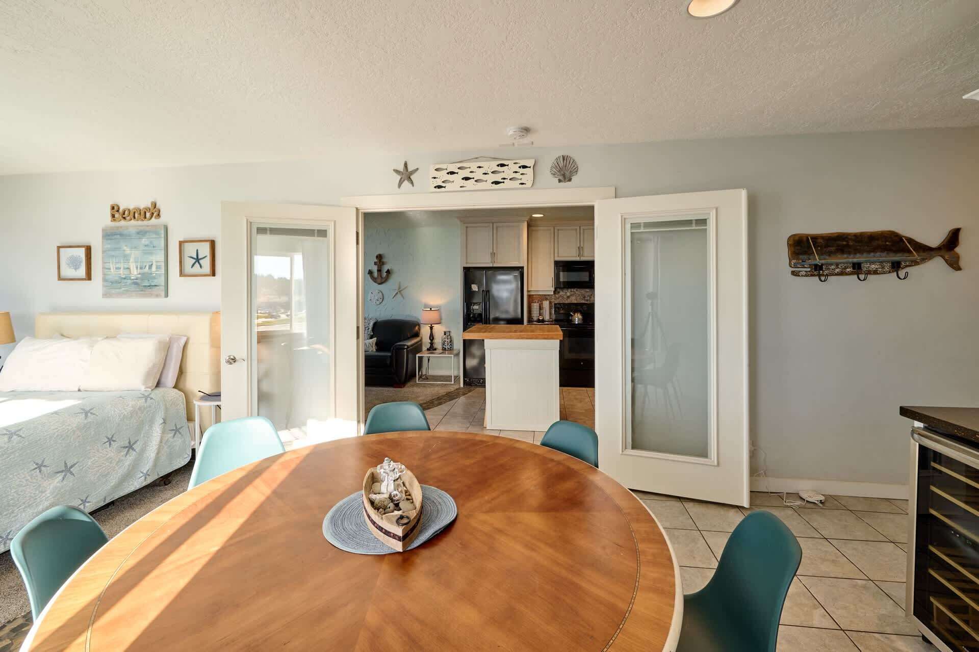 Una stanza con un letto, un tavolo da pranzo con sedie, una zona cucina e vista attraverso una porta aperta.