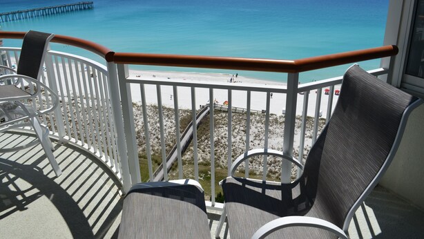 A balcony with a view of the beach and ocean.