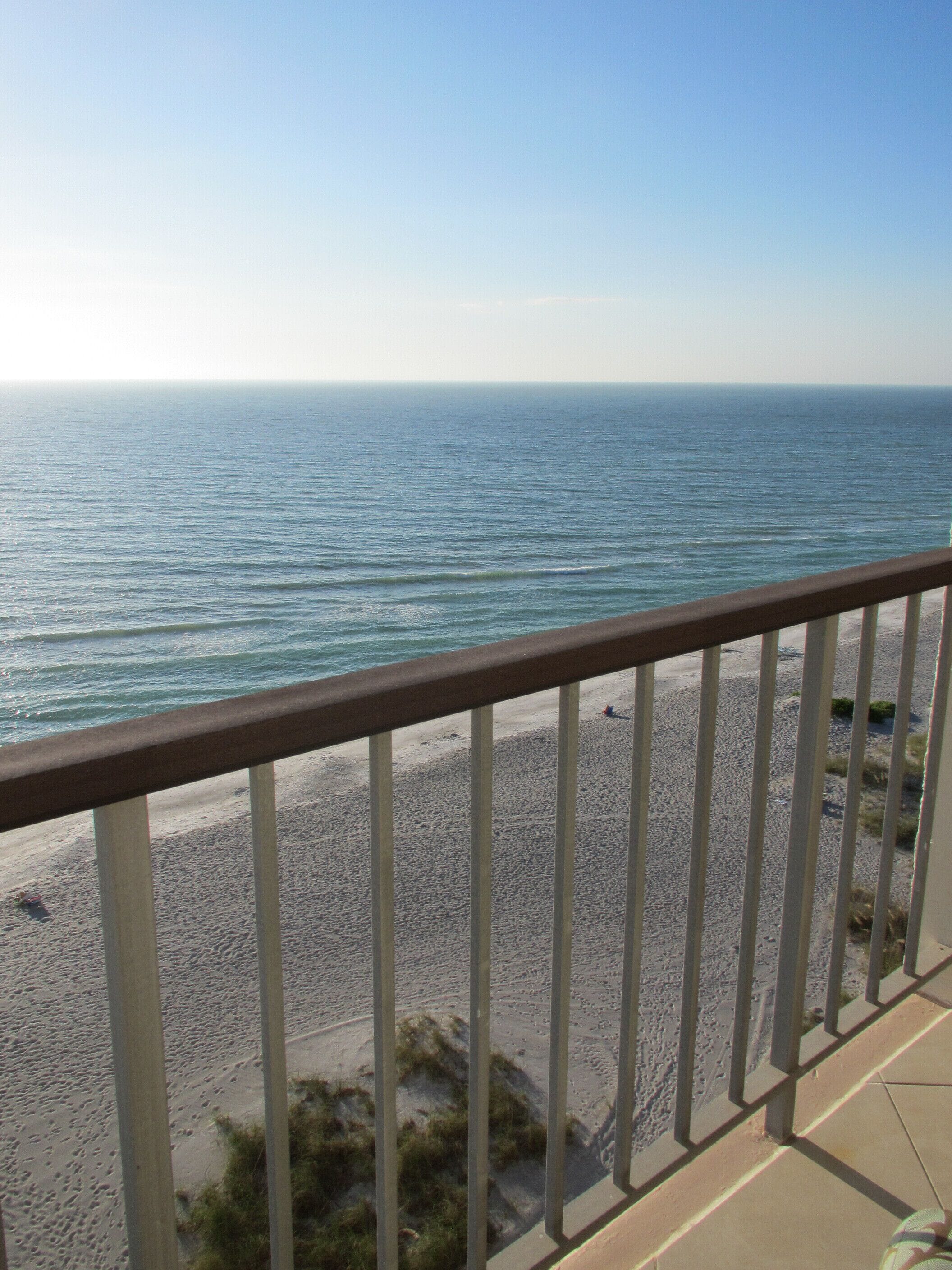 Ein Balkon mit Blick auf einen Sandstrand und das Meer.