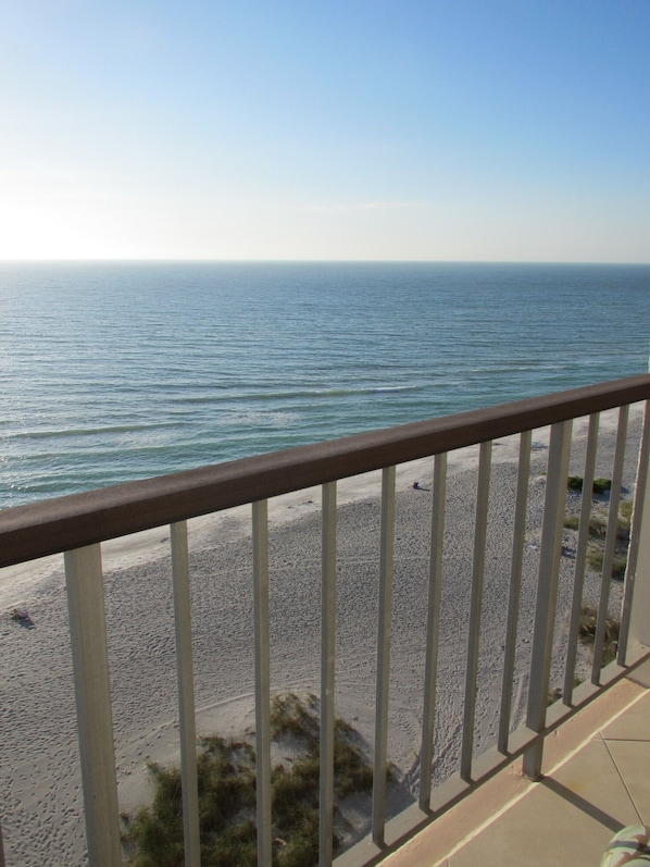A balcony with a view of a sandy beach and the ocean.