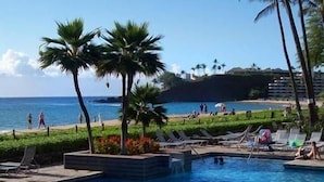 Un espace piscine doté de chaises longues, d’un jacuzzi et offrant une vue sur la plage et l’océan.