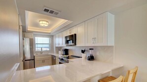 A modern kitchen with white cabinetry, a central island, and a built-in microwave.