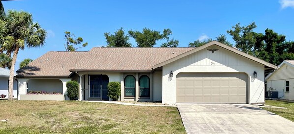 A single-story house with a beige garage door, a front entrance with a dark door, and a small porch area.
