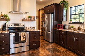 A modern kitchen with stainless steel appliances, dark wood cabinets, and a window providing natural light.