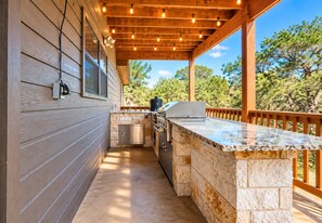 An outdoor kitchen with a stone countertop, a grill, and a sink.