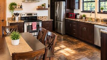 Una cocina moderna con armarios de madera oscura, electrodomésticos de acero inoxidable y un comedor con mesa y sillas de madera.