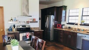 Una cocina moderna con armarios de madera oscura, electrodomésticos de acero inoxidable y un comedor con sillas y mesa de madera.