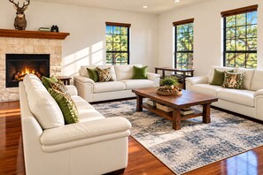 A spacious living room with a fireplace, leather sofas, and large windows.