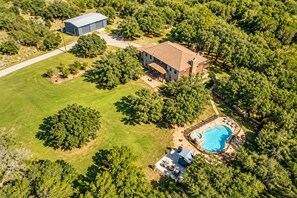 An aerial view of a residential property with a large house, a swimming pool, and a garage. - RETREAT NEXT TO FLAT CREEK WINERY, Pool,Billiard Table,Outdoor Kitchen, Fire Pit (Marble Falls)