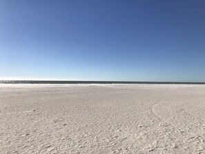 Ein weiter, offener Sandstrand mit blauem, klarem Himmel.