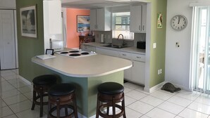 Una cocina con isla central, taburetes de bar, un reloj y una tortuga en el suelo.