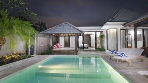 Un espace piscine doté d’un coin salon couvert, d’une chaise longue et d’un lit.