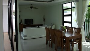 Ein modernes Wohnzimmer mit einer Couch, Fernseher, Esstisch und Stühlen.