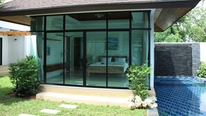 Ein modernes Haus mit Glastür, die zu einem Schlafzimmer mit Bett und Nachttisch führt.
