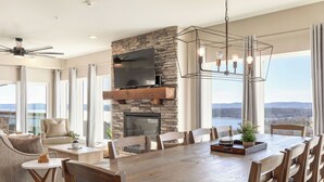 A spacious living area with a stone fireplace, a large flat-screen TV, and a dining table set for six. - Table Rock views, Indoor pool, private hot tub (Branson)
