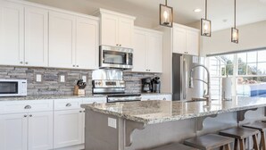 A modern kitchen with white cabinets, granite countertops, stainless steel appliances, and bar stools. - Table Rock views, Indoor pool, private hot tub (Branson)