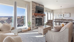 A spacious living room with a stone fireplace, large windows offering a city view, and modern furniture. - Table Rock views, Indoor pool, private hot tub (Branson)
