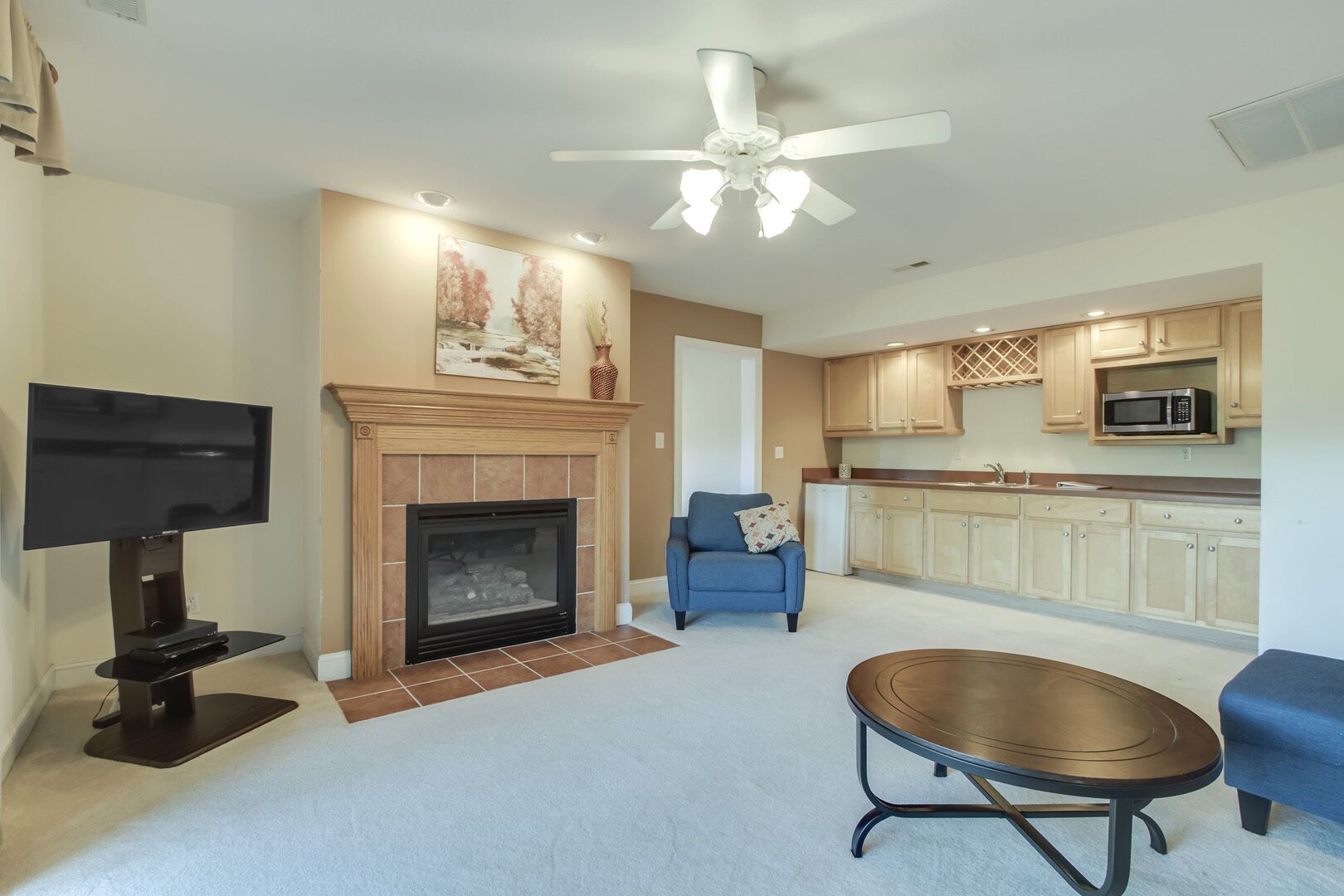 A living room with a fireplace, a television, a blue armchair, and a round coffee table.