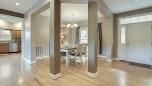 A spacious living area with hardwood flooring, a dining table with chairs, a chandelier, and a kitchen in the background. - • Reserve TOQUA COVES • Family Friendly • Lake Access • Two Decks • Sleeps 6+ (Loudon)