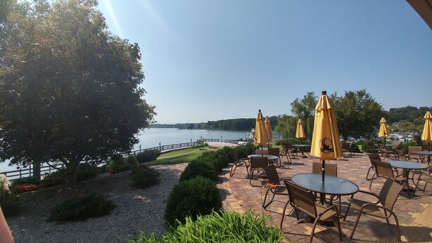 An outdoor patio with tables and chairs, yellow umbrellas, and a view of a lake. - • Reserve TOQUA COVES • Family Friendly • Lake Access • Two Decks • Sleeps 6+ (Loudon)