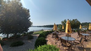 An outdoor patio with tables and chairs, yellow umbrellas, and a view of a lake. - • Reserve TOQUA COVES • Family Friendly • Lake Access • Two Decks • Sleeps 6+ (Loudon)