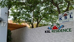 Señal para KSL Residence, con un logo que presenta palmeras y una montaña.