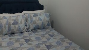 Un dormitorio con cama, cortinas, aire acondicionado y una lámpara en el techo.
