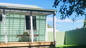 A small house with a porch, a table, and two chairs.