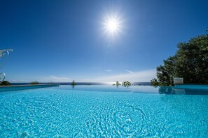 A clear blue sky, a bright sun, and a swimming pool with a view of the ocean. - Villa with pool and garden for exclusive use (Corsano)