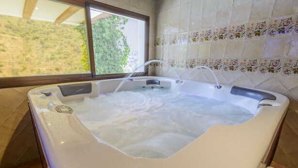 Een bubbelbad met uitzicht door een raam op een heuvel.