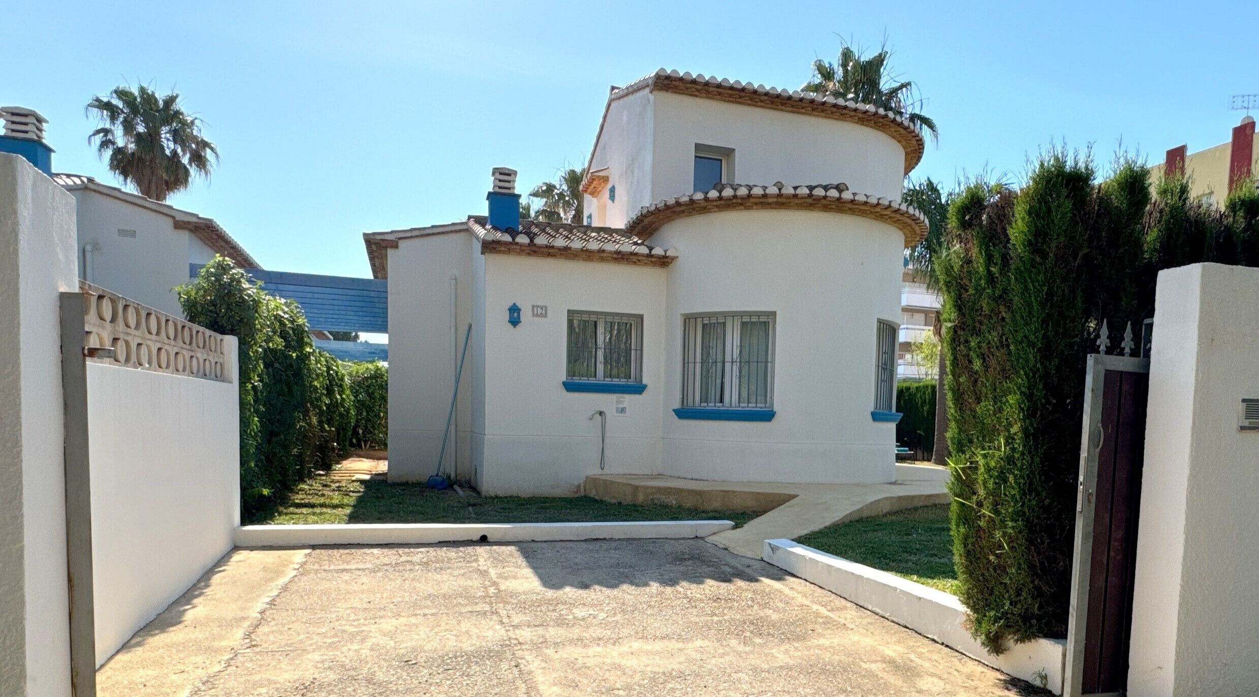 A two-story house with a tiled roof, a small front yard, and a gate.