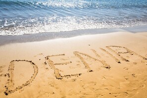 Una playa con la palabra "DENIA" escrita en la arena.