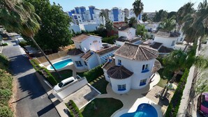 A residential area with multiple white buildings, a swimming pool, and a curved driveway.