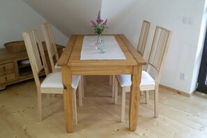 Ein Holztisch mit weißen Stühlen, eine Vase mit Blumen und eine weiße Tischläufer.